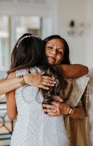 Emotional mother and bride share a tender hug, mother wearing traditional Indian saree at wedding.