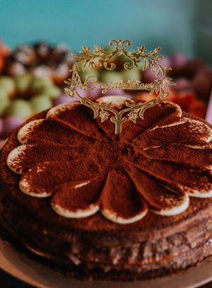 Elegant tiramisu wedding cake topped with a gold Congratulations cake topper dusted with cocoa powder.