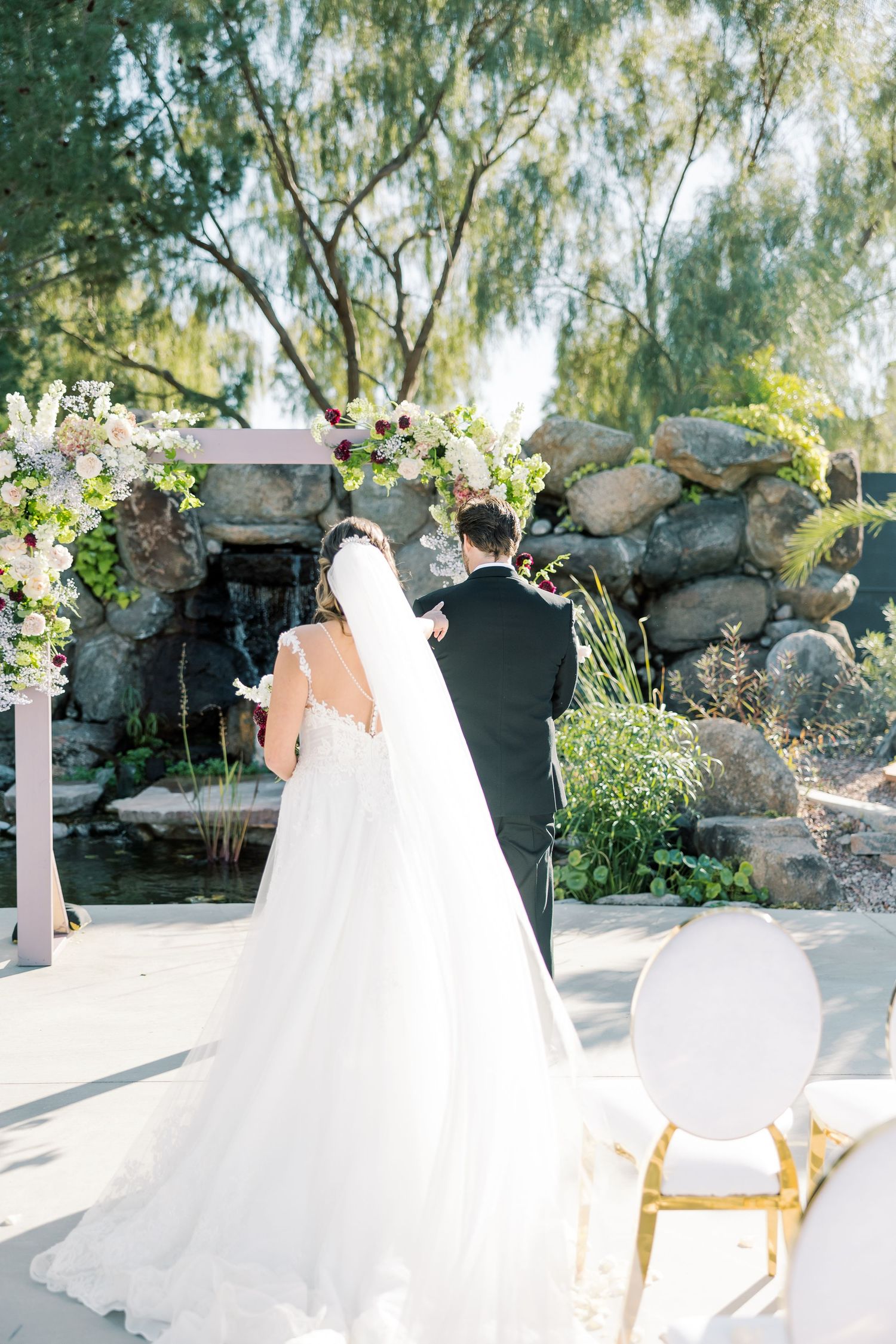 A flowing white wedding dress captured in a garden setting with natural greenery.