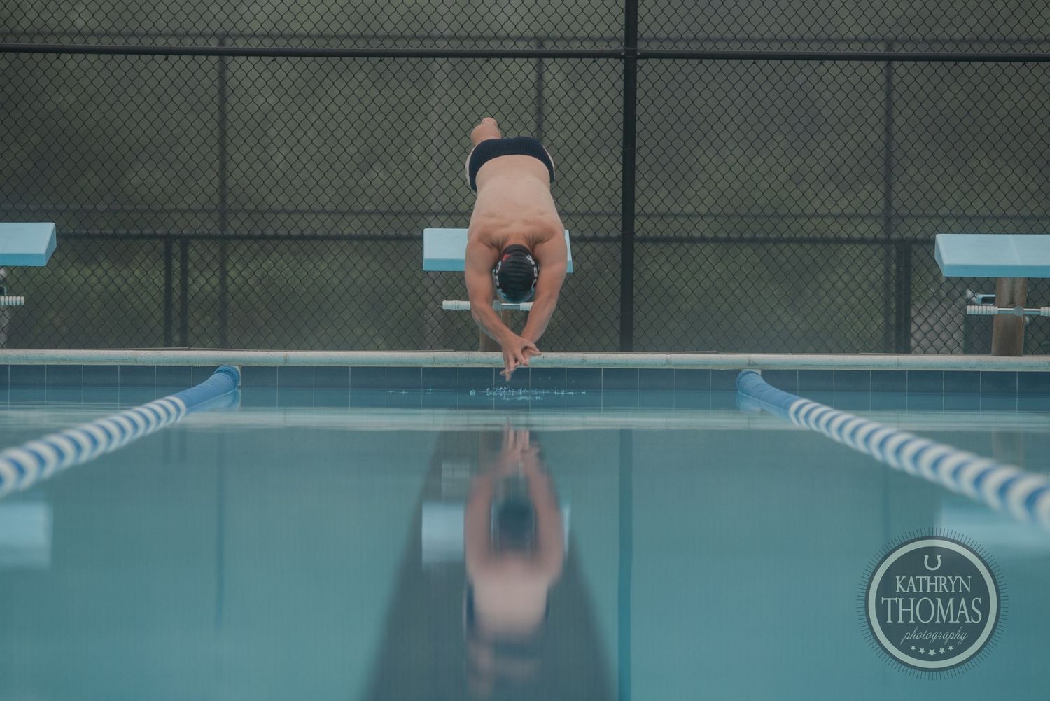 A swimmer dives into the pool creating a perfect reflection in the water.