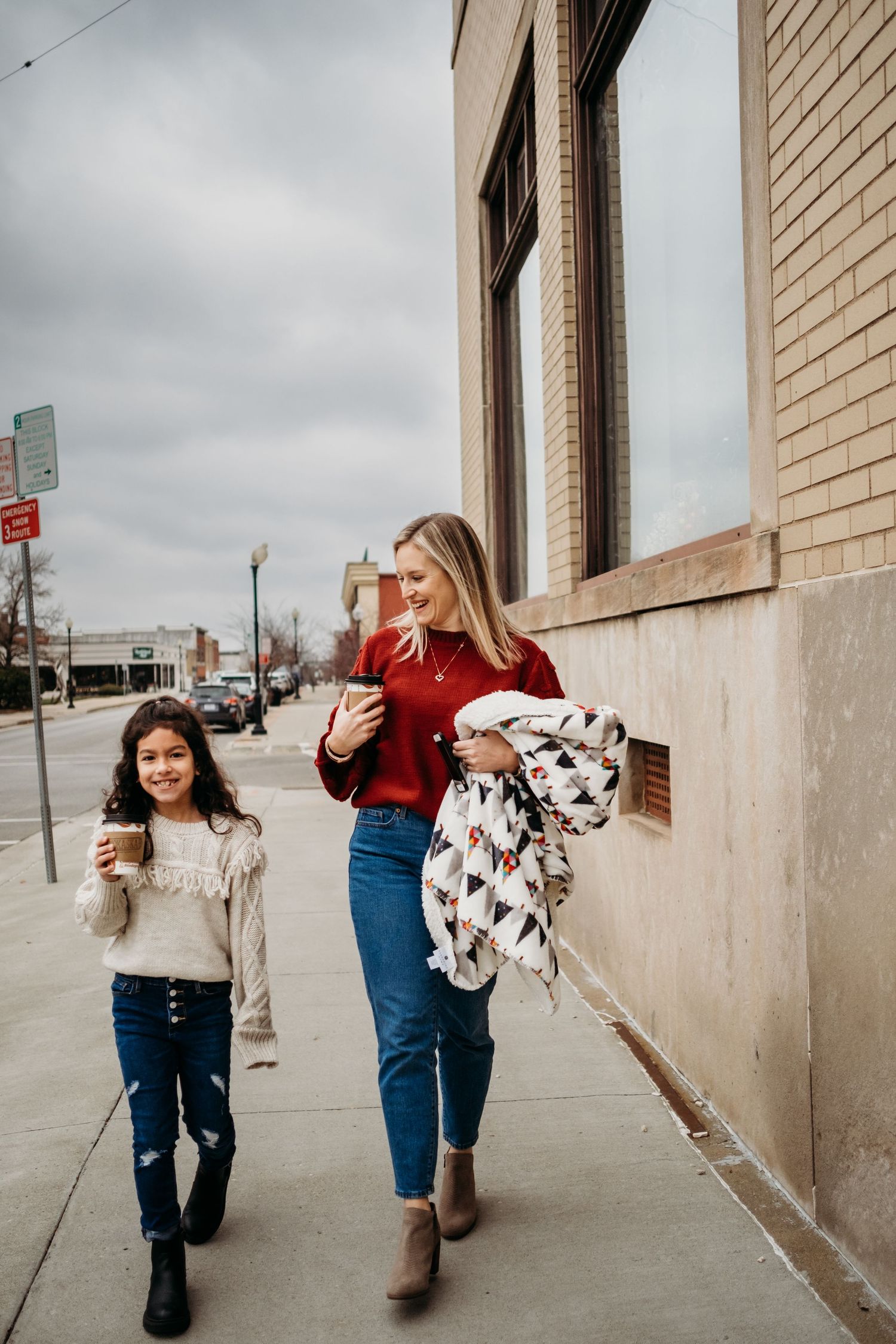 A mom and daugher walk together smiling in downtown St. Joseph, Missouri for a photography session.