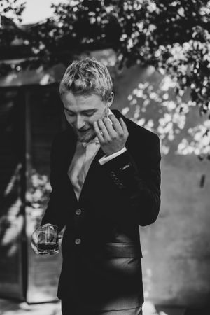 Black and white portrait of a person in formal attire holding a glass.