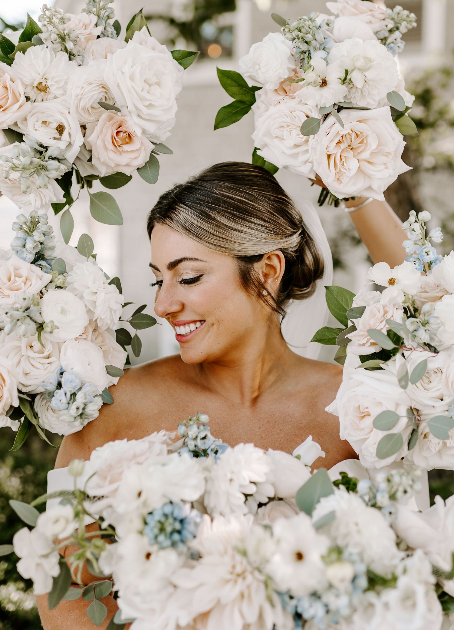 Bride surrounded by delicate white and blush floral arrangements.