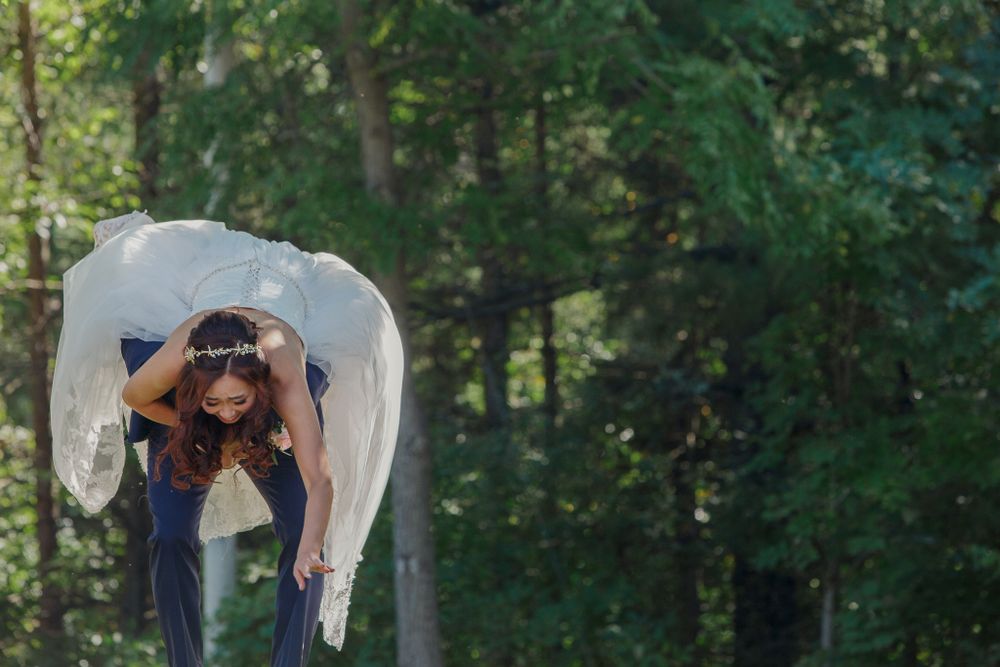 Playful wedding photograph with veil flowing in forest setting.