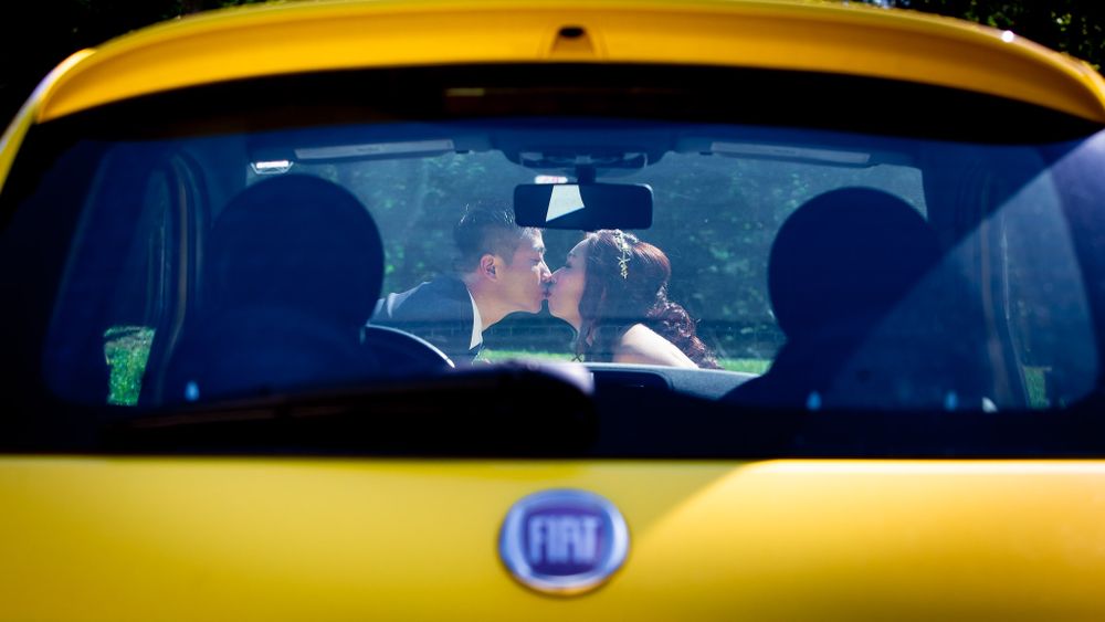 Romantic moment captured through yellow Fiat car windshield.