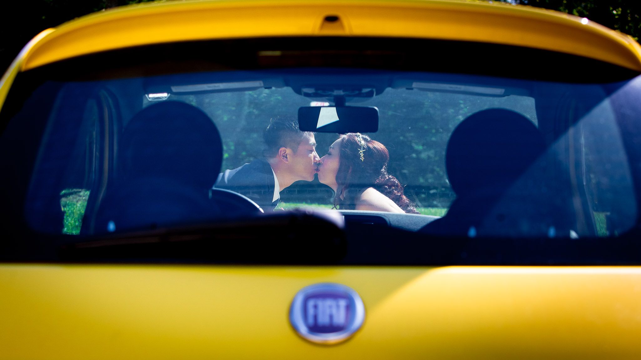 Romantic moment captured through yellow Fiat car windshield.