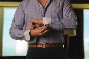 Male boudoir image of a man in a suit slowly undressing by undoing his cufflinks.