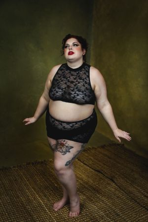 Plus size intimate fashion photography with black lace crop top and leg tattoo in artistic studio setting in Las Vegas.