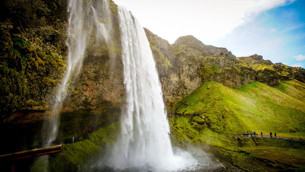 Majestic waterfall plunges down green cliffside in dramatic landscape view.