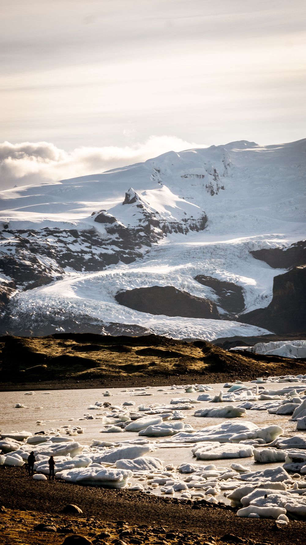 Snow-covered mountain landscape with scattered ice chunks in the foreground.