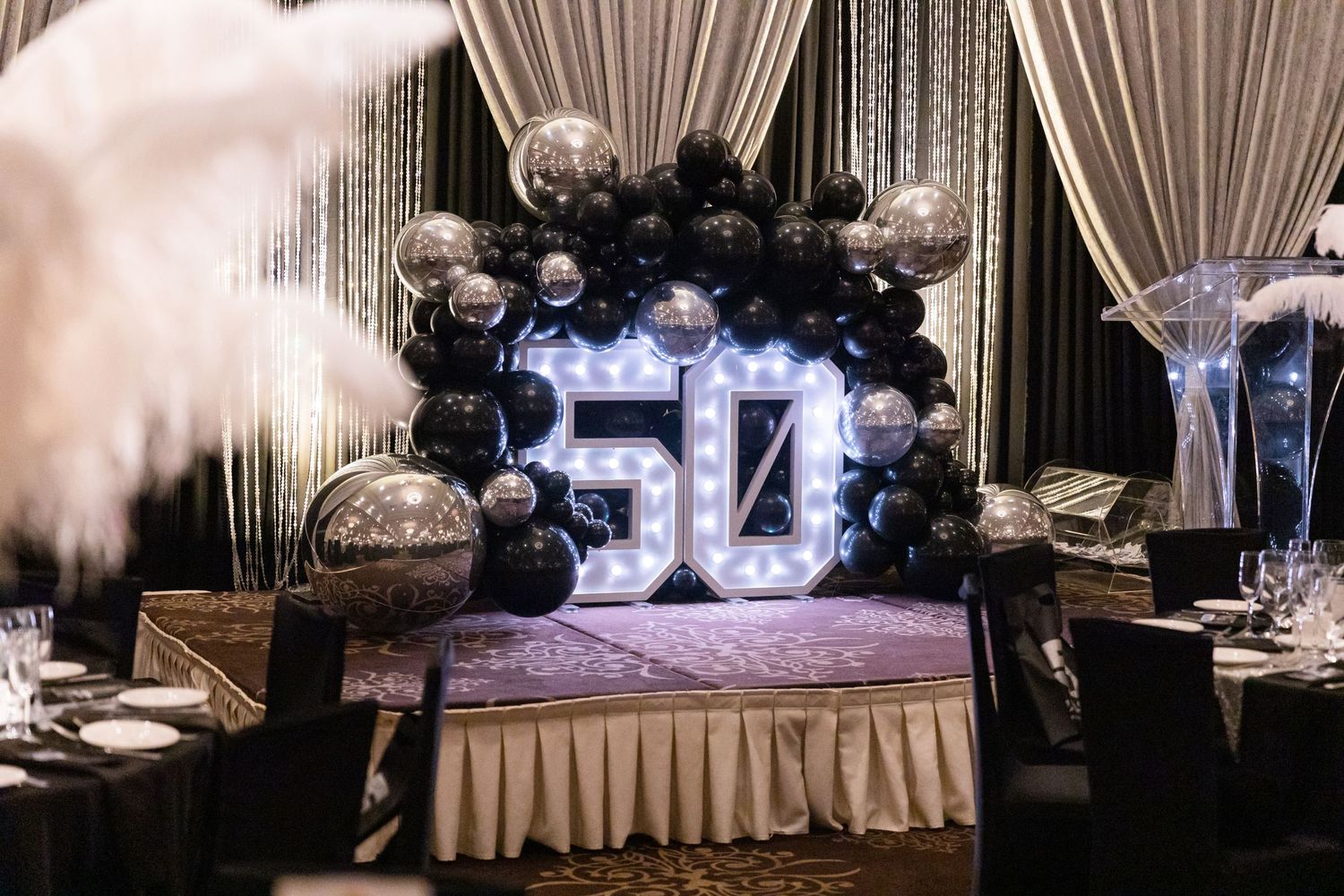 Elegant white draped event space with dramatic lighting and decorative elements.