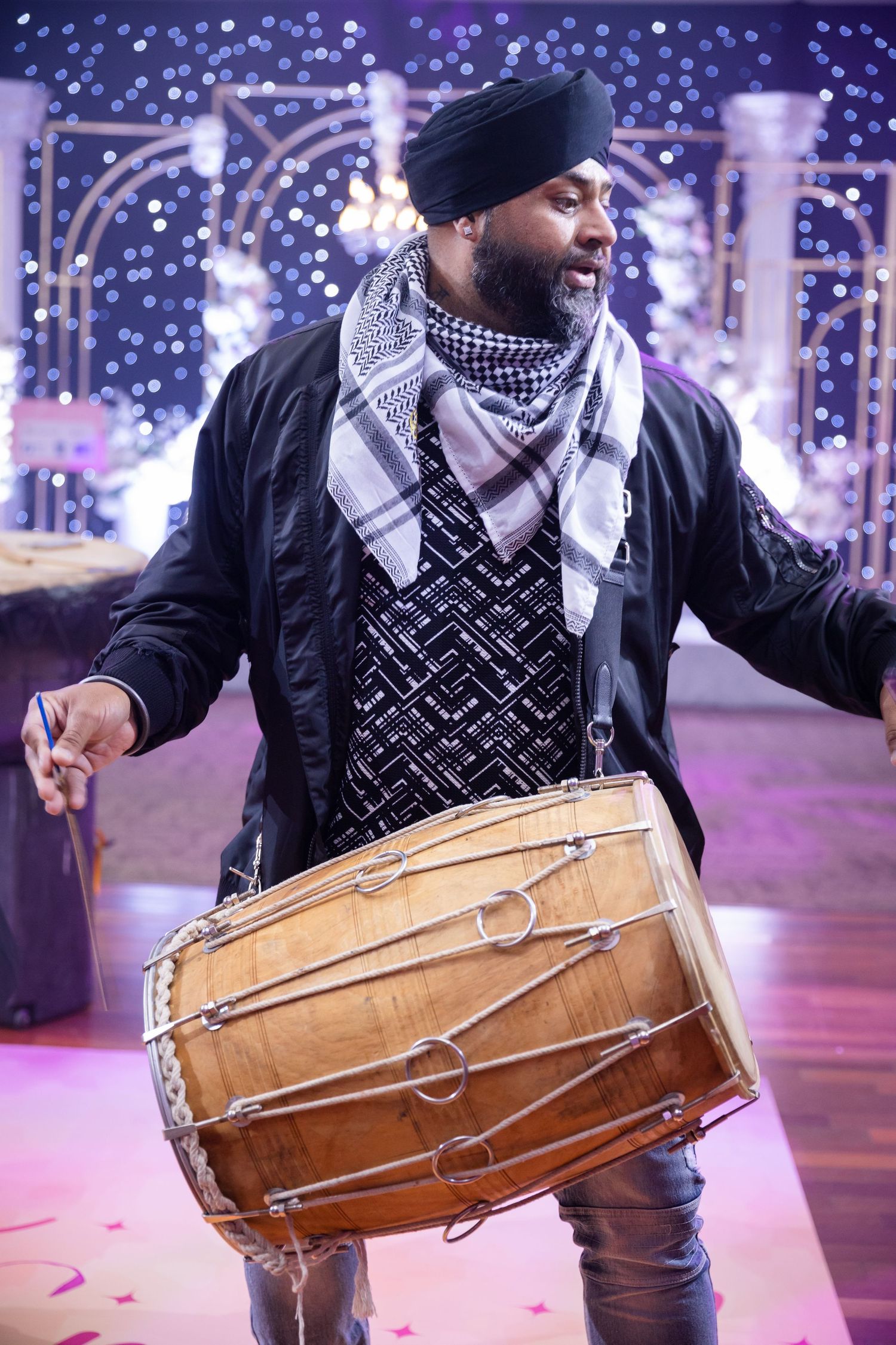 Performer playing traditional wooden drums with festive lights in background.