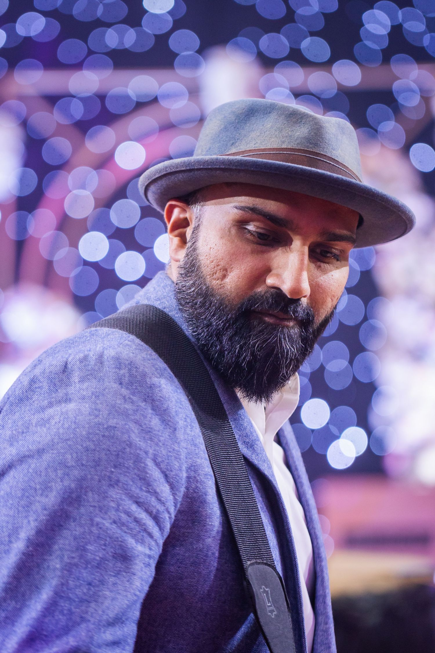 Performer in winter attire against blurred purple bokeh lights.