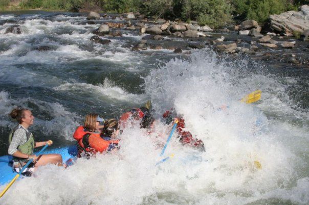 group on a raft crashing into a wave while whitewater rafting