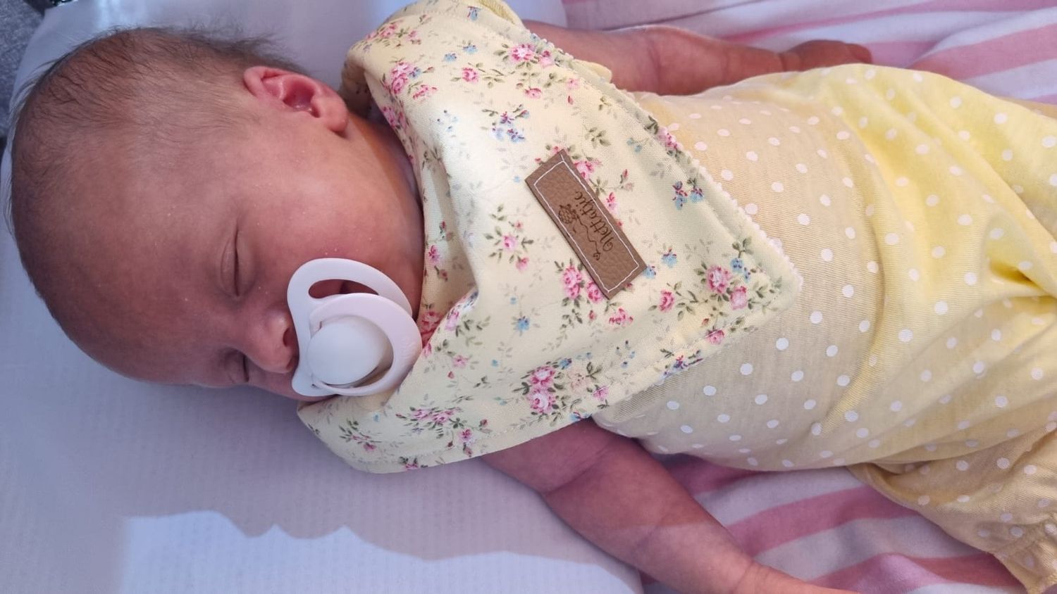 Sleeping newborn baby wrapped in floral print swaddle blanket.