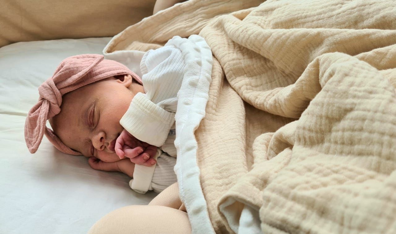 Baby resting on cream colored textured blanket.