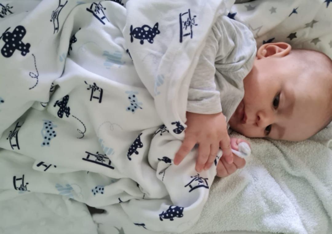 Baby lying on light blue fabric with navy pattern print.