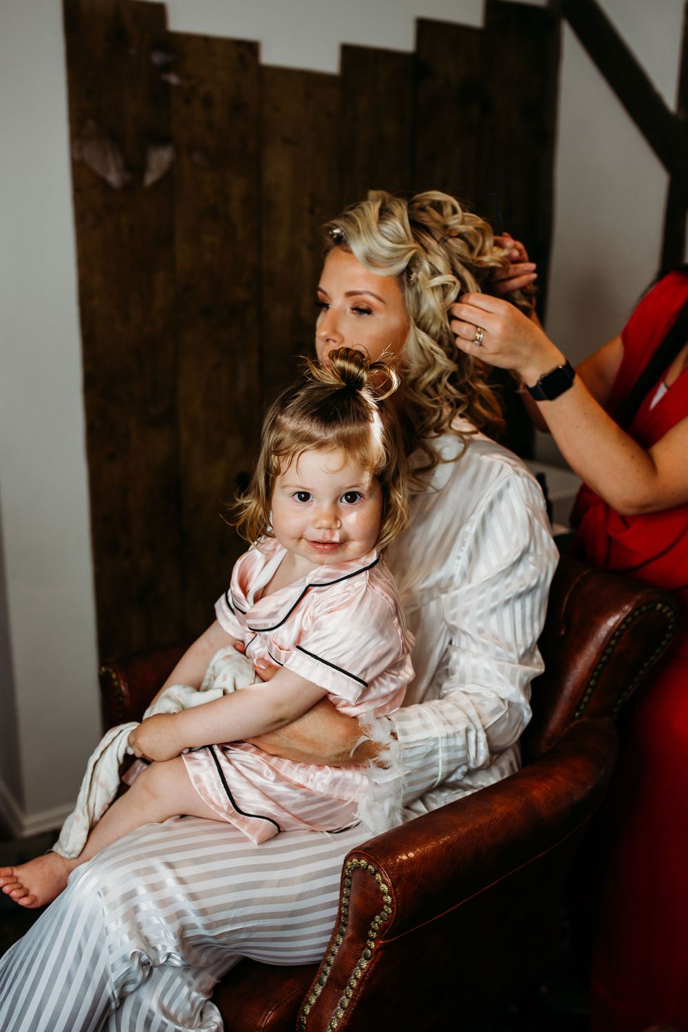 Getting ready moment during wedding preparations with vintage leather chair and wood backdrop.