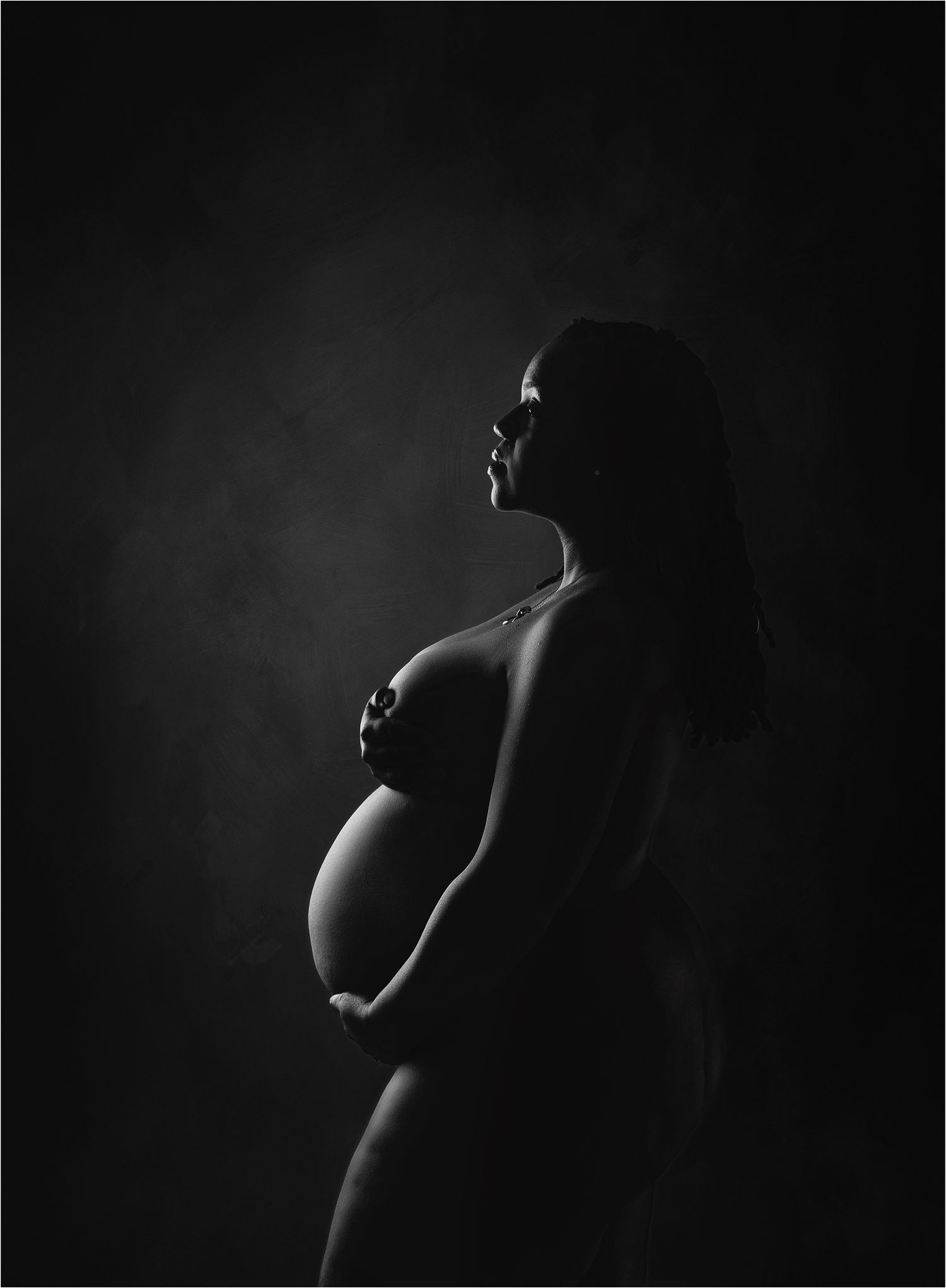 Black and white silhoutte of pregnant woman posed in the Austin Newborn PHotography studio.  back lit with rim light