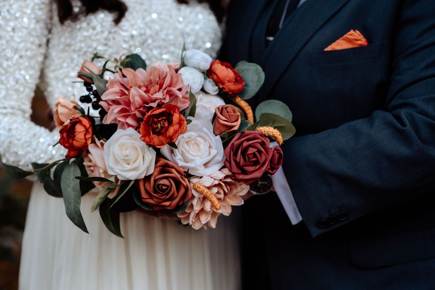 LGBTQ+ same sex lesbian couple show off wedding dress, suit, and bouquet