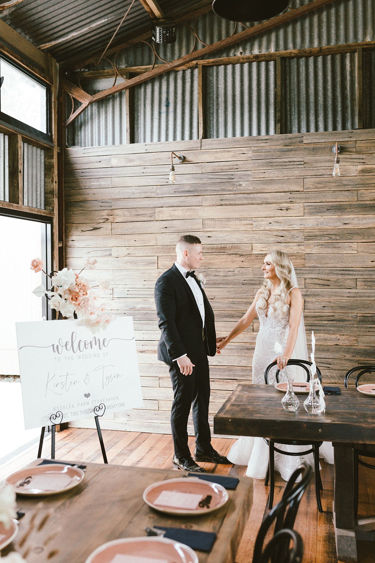 Indoor wedding venue with white decor and rustic wood paneled walls and signage.