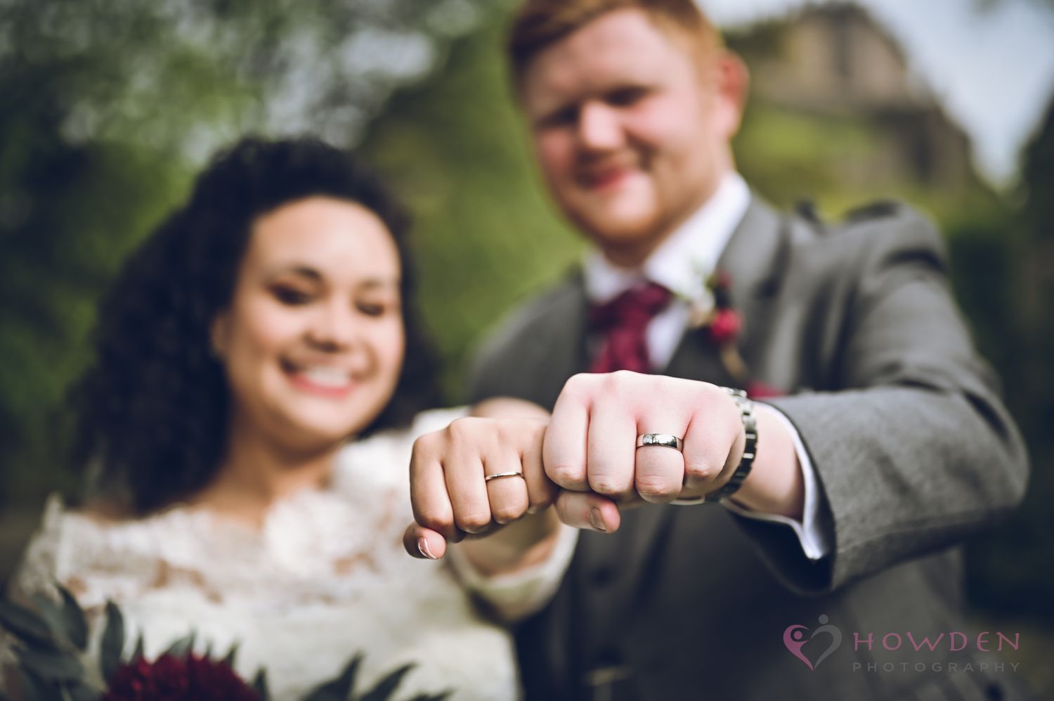A close-up shot of wedding rings displayed on hands during an outdoor ceremony.