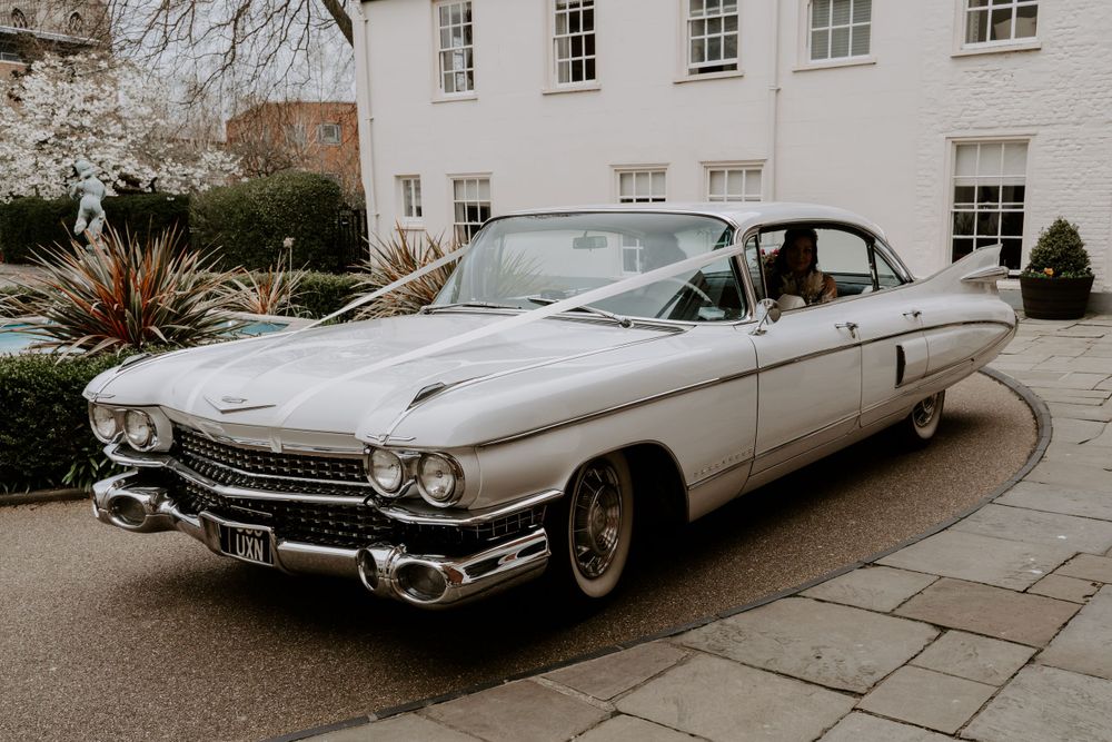 a white cadillac wedding car with a white ribbon on the front