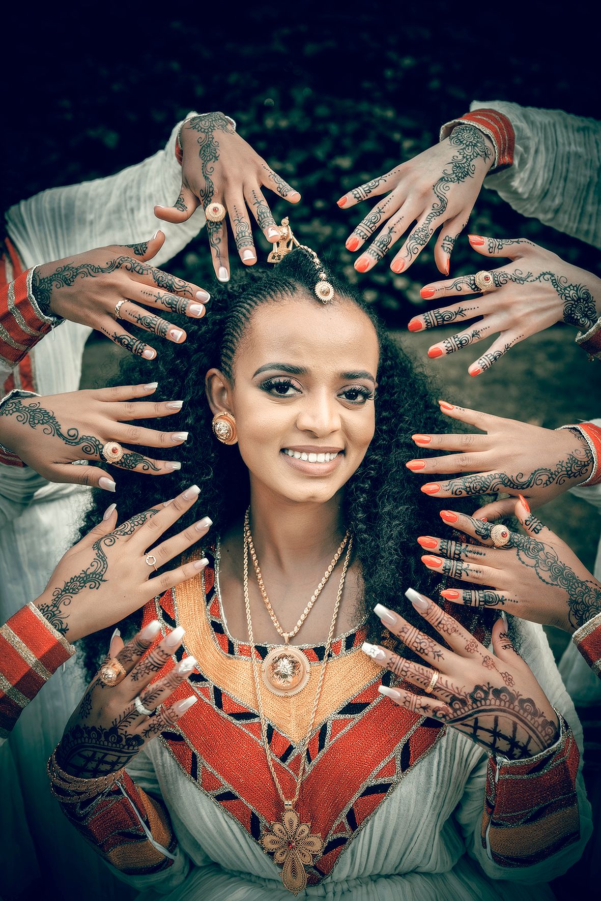 Multiple hands with henna designs frame a portrait wearing traditional jewelry and clothing.