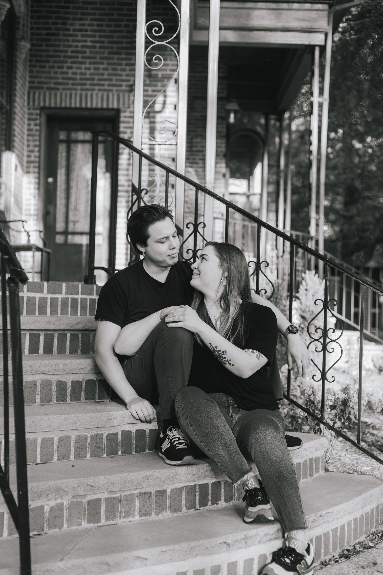 Couple sharing a candid moment while sitting on brick steps of a historic building.