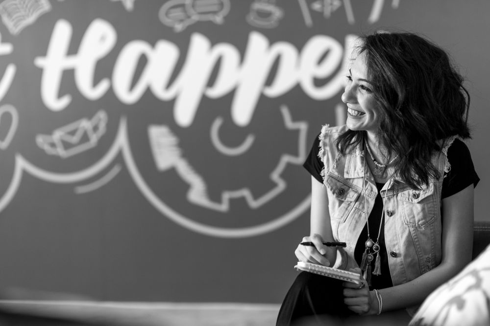 Professional speaker giving an inspirational talk in front of a wall with motivational text.