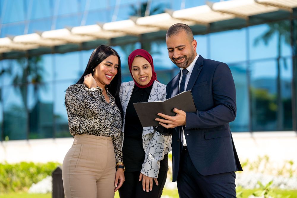 Business team reviewing information on tablet device outside modern office building.