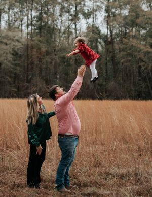 Playful moment captured in a golden field as a child is lifted high into the air.