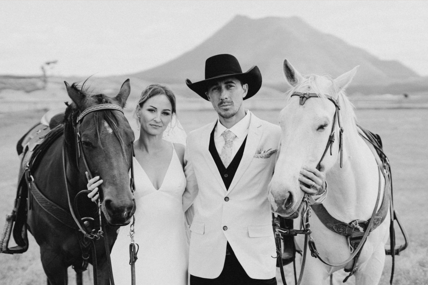 bride and groom looking at camera with horses
