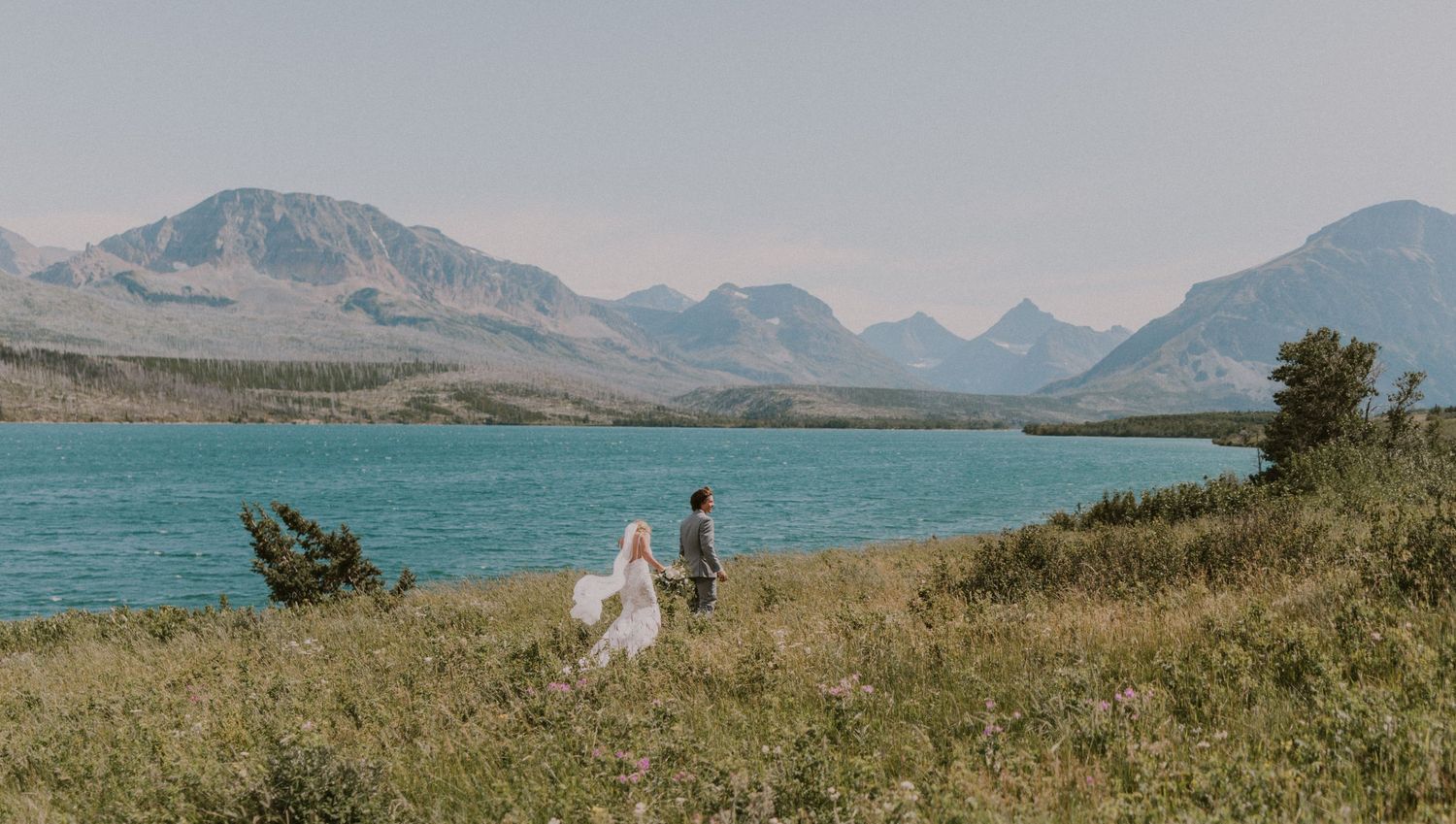 Couple eloping in the mountians with a beautiful blue lake behind them