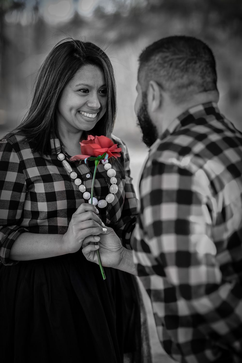 A romantic black and white photo series featuring a couple with a red rose against a blurred background.
