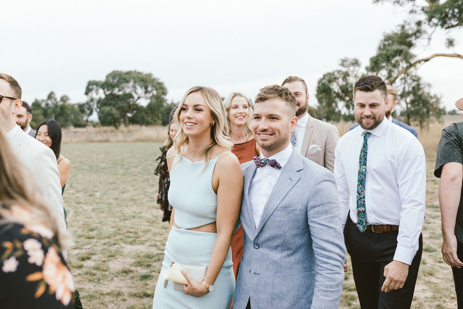 Wedding guests in stylish attire mingling at an outdoor celebration.