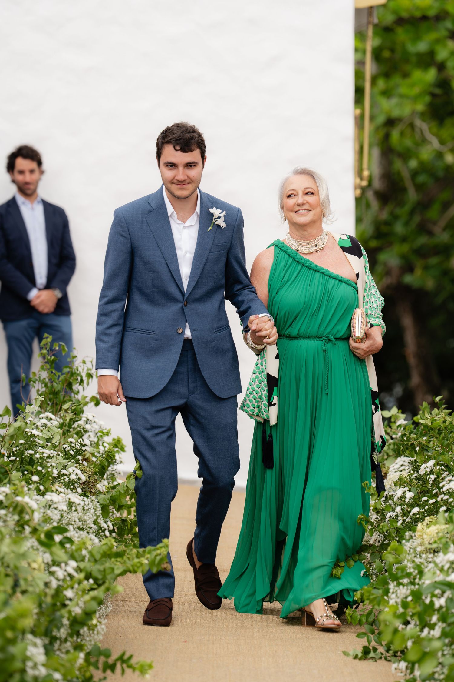 Wedding processional on garden path with attendant in emerald green dress.