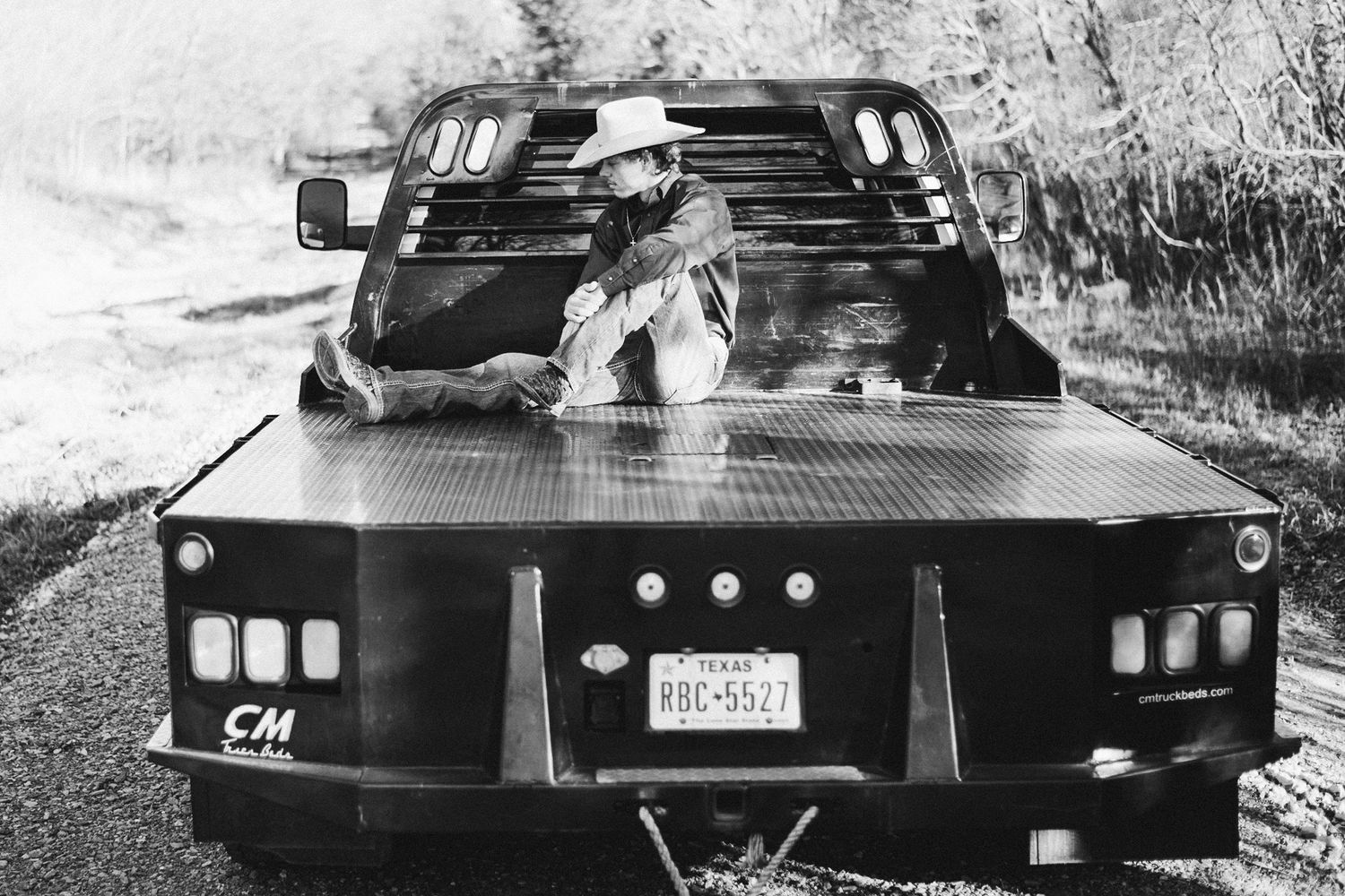 Black and white photo of boots visible through truck bed window.