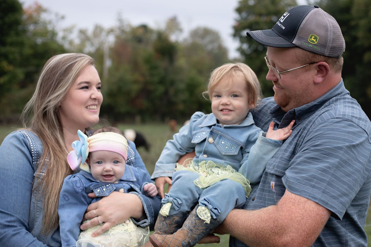 A happy family sitting together outdoors sharing joyful moments with their young children.