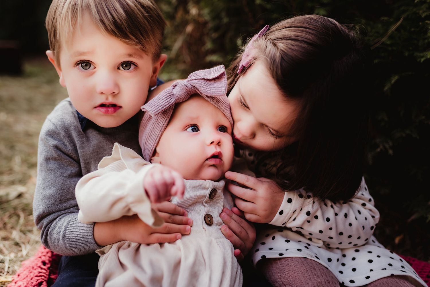Three siblings share an intimate moment together during an outdoor photoshoot.