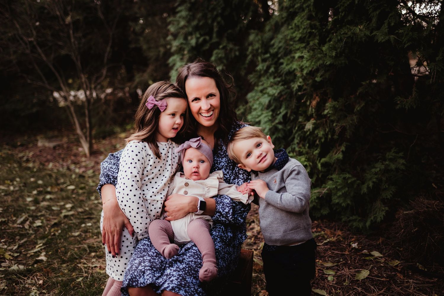 An intimate family portrait captured outdoors with greenery in the background.