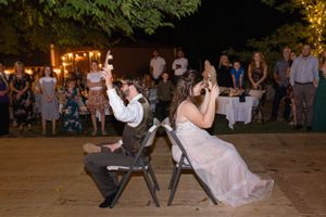 bride and groom playing shoe game with tree with lights around it behind them in Orland, California Wedding