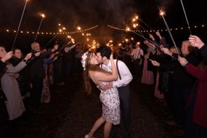 Bride and groom kissing at end of sparkler exit with lights above them after Orland, California Wedding