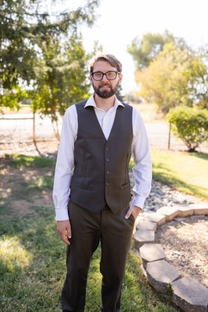 Groom portraits at Orland, California Wedding in the fall. The groom is standing on the grass with trees behind him.