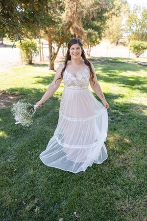 Bride twirling in dress on lawn right before wedding at Orland, California Wedding