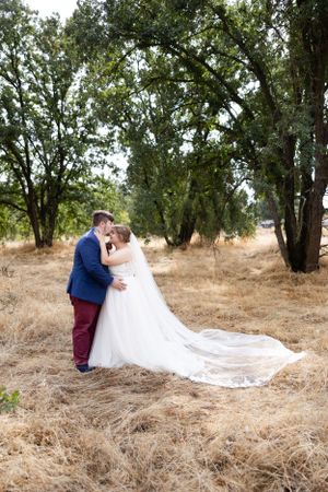 full body image of Bride and groom in field with trees in Chico, California Wedding
