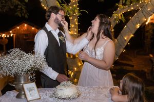 Bride and groom feeding each other cake during wedding reception with tree with lights in Orland, California Wedding