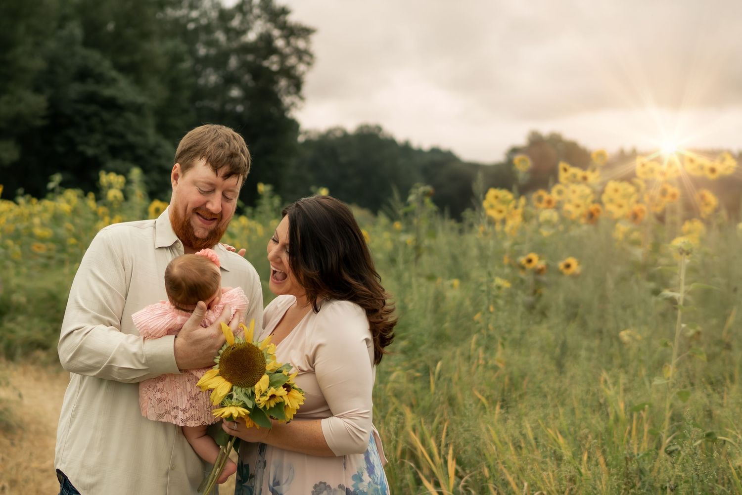 Family shares an intimate moment in a sunlit meadow with yellow wildflowers.