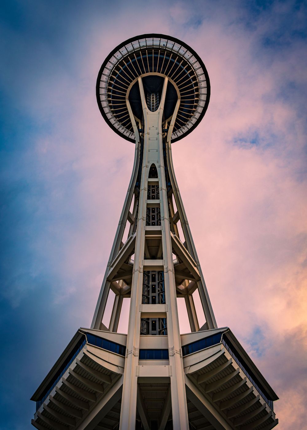 Seattle Space Needle tower photographed from below against pink and blue sunset sky.