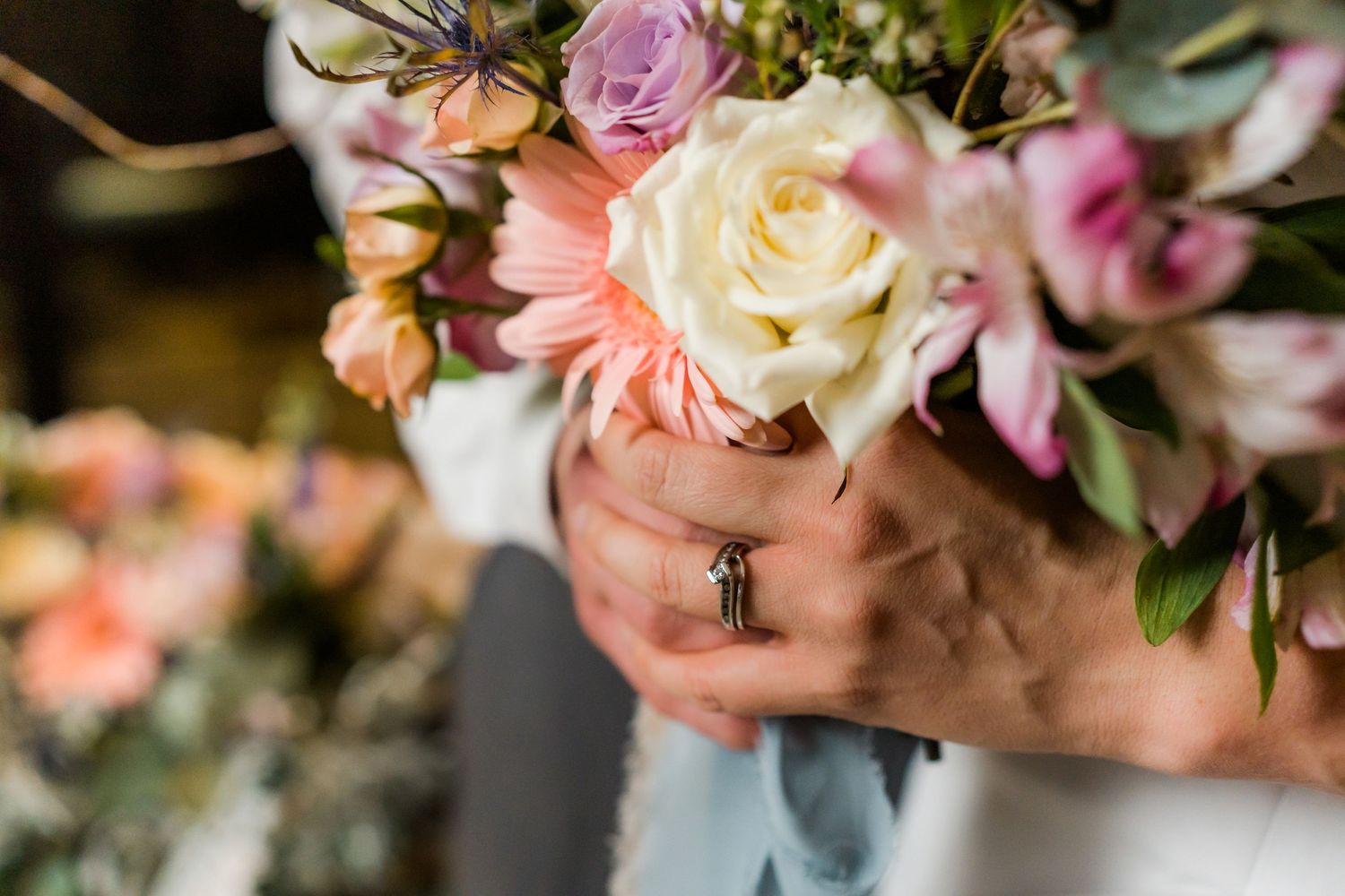 bouquet of flowers held by bride and groom showing off the ring